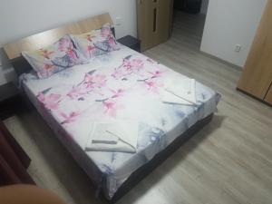 een bed met roze bloemen op een kamer bij WaveSea Apartment in Eforie Nord
