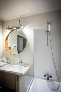 a bathroom with a shower and a sink and a mirror at Oustau Camarguen Hôtel & Spa in Le Grau-du-Roi