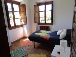 a small bedroom with a bed and two windows at Casa Estrella in Pravia