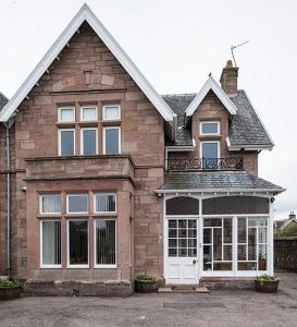 a large brick house with a white door at Eastdene Guest House in Inverness