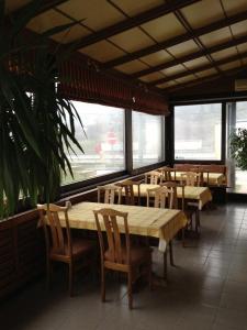 a restaurant with wooden tables and chairs and windows at Panoráma Panzió in Tatabánya