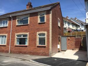 a red brick house with a balcony on a street at Stunning, Newly Renovated, Townhouse in Central Dawlish in Dawlish