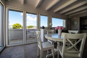a dining room with a table and chairs and windows at Bianca Dimora in Torre Canne