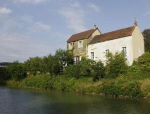 un grand bâtiment au bord d'une rivière dans l'établissement Le Clos Du Murier, à Chassignelles