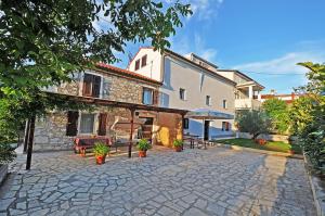 a building with a patio with a table and chairs at Apartment Dva Oriha in Funtana