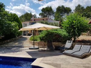un patio con sillas, una sombrilla y una piscina en B&B Les Grillons, en Draguignan