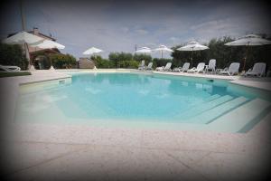 a large swimming pool with chairs and umbrellas at Agriturismo Panorama in Castelnuovo del Garda