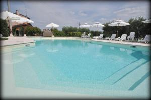 a large blue swimming pool with chairs and umbrellas at Agriturismo Panorama in Castelnuovo del Garda