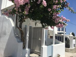uma árvore em frente a uma casa branca com flores cor-de-rosa em Mina Studios em Platis Gialos, Mykonos