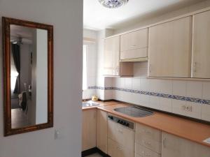 a kitchen with white cabinets and a mirror at APplaya in El Puerto de Santa María