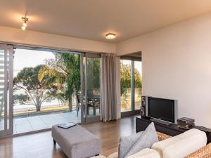 ein Wohnzimmer mit einem Sofa und einem TV in der Unterkunft Sea Spray Suites - Heritage Collection in Paihia