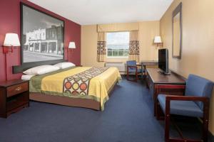 a hotel room with a bed and a desk and a television at Super 8 by Wyndham Big Cabin/Vinita Area in Vinita