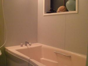 a bathroom with a tub and a sink and a mirror at Numazu Ikyuuan 沼津一休庵 in Numazu