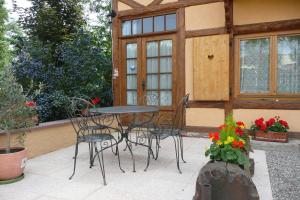 un patio con mesa, sillas y flores en Gite de la Streng en Ribeauvillé