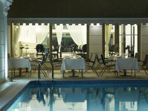 スパルティにあるMenelaion Hotelのプーラステリヤステリヤステリの隣にテーブルと椅子が備わるスイミングプール