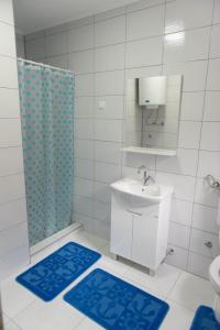 a bathroom with a sink and a shower and blue mats at Apartmani ELEGANCE Tuzla in Tuzla +50 photos