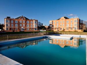 una piscina d'acqua di fronte a due edifici di Exe Zarzuela Park a Madrid