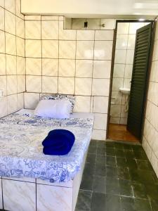 uma cama com uma almofada azul num quarto em Kitnet BH em Belo Horizonte