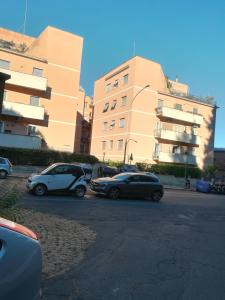 due auto parcheggiate in un parcheggio di fronte a un edificio di Holiday Home Roma a Roma