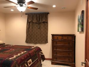 um quarto com uma cama, uma cómoda e uma ventoinha de tecto em Delta Dome Home Basement Apartment em Delta Junction
