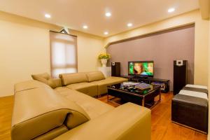 uma sala de estar com um sofá e uma televisão de ecrã plano em Hliweng B&B em Yilan City