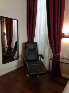 a black chair sitting in a room with a mirror at 1suite firenze in Florence