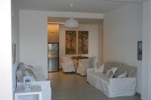 ein Wohnzimmer mit weißen Möbeln und einem Tisch in der Unterkunft Thalassa Apartment in Kallirákhi