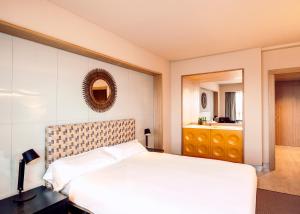 a bedroom with a white bed and a bathroom at Barceló León Conde Luna in León