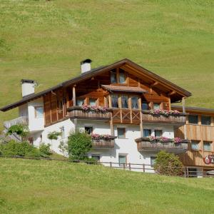 una casa en una colina con flores en el balcón en Residence Araldina, en San Cassiano