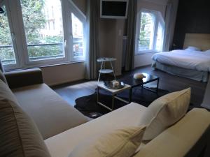 a living room with a couch and a bed and windows at Les Carmes in Rouen