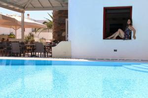 a woman sitting in a window next to a swimming pool at Annita's Village Hotel in Agia Anna Naxos