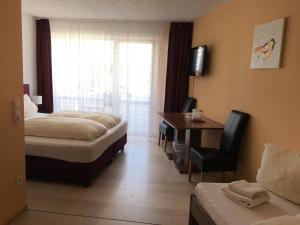 Cette chambre comprend deux lits, un bureau et une fenêtre. dans l'établissement Hotel Hafez, à Bad Salzuflen