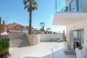 a building with stairs and a palm tree on a beach at Porto Demo Hotel in Agios Georgios Pagon