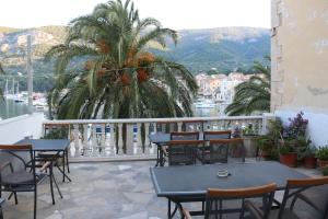 a balcony with tables and chairs and a palm tree at The Little Gem in Komiža