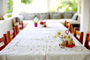 una mesa larga con mantel blanco y flores. en Sulo Pension en Patara