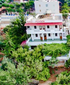 un edificio blanco con techo rojo rodeado de árboles en Sulo Pension en Patara