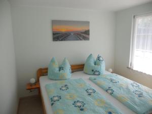 1 dormitorio con 1 cama con almohadas azules en Ferienhaus Vorwachs 5 en Schwielochsee