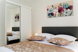 een slaapkamer met een bed met 2 kussens en een spiegel bij Apartmani Gaby in Trogir