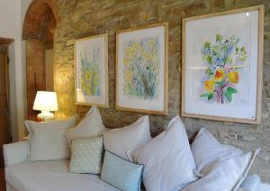 a white couch against a stone wall with paintings at Antico Casale Rodilosso in Montaione