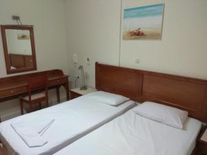 a bedroom with two beds and a desk and a mirror at Captain Yiannis Studios & Apartments in Kos