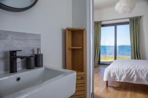 a bathroom with a sink and a bed and a window at Stay on the Bay, Skye in Broadford