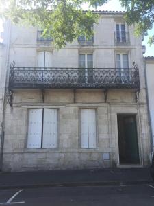 a stone building with white doors and a balcony at L'Escale in Rochefort