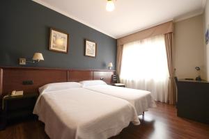 a bedroom with two white beds and a window at Hospedaxe A Vila in A Pobra do Caramiñal