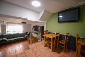 sala de estar con sofá, mesa y TV en Hospedaxe A Vila, en Pobra do Caramiñal