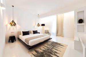 a white bedroom with a bed and a rug at Paros Agnanti Resort & Spa in Parikia