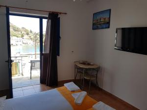1 dormitorio con cama, TV y balcón en LydiaMare, en Agios Kirykos