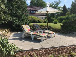2 sillas y una sombrilla en el patio en Villa Seeidyll, en Prieros