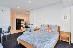 a bedroom with a large bed and a kitchen at Stunning Harbour & City View Studio l AIRCON & WIFI in Auckland