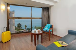 ein Wohnzimmer mit einem Sofa, einem Tisch und einem Fenster in der Unterkunft Leonardo Hotel Tiberias in Tiberias