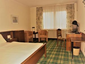 バート・ローテンフェルデにあるHotel Villa Luiseのベッドとデスクが備わるホテルルームです。